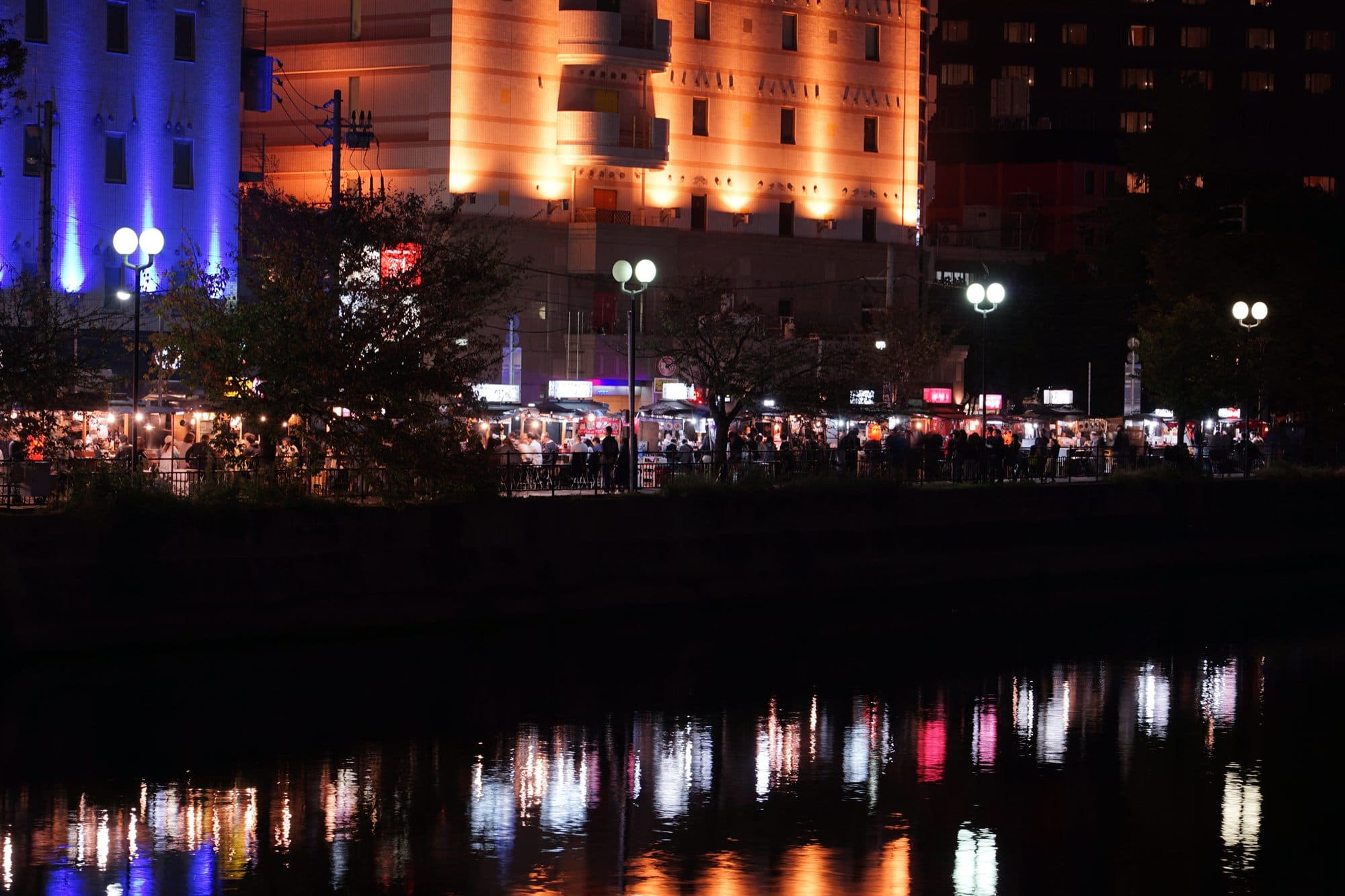 Lit food stalls along the Naka River at Nakasu, reflected in the water