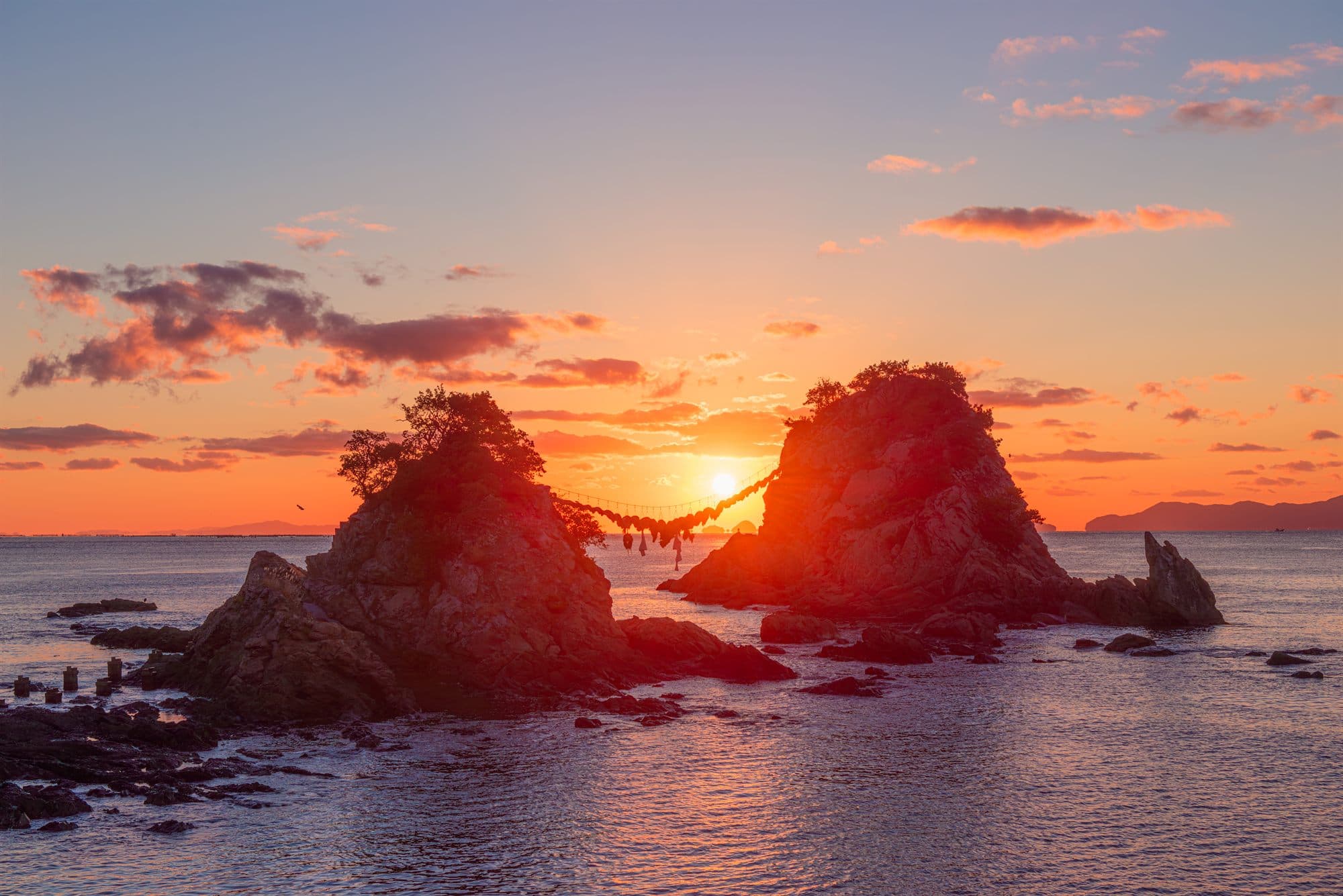 Two rocks joined by a straw rope, silhouetted against the sunset off the Itoshima coast